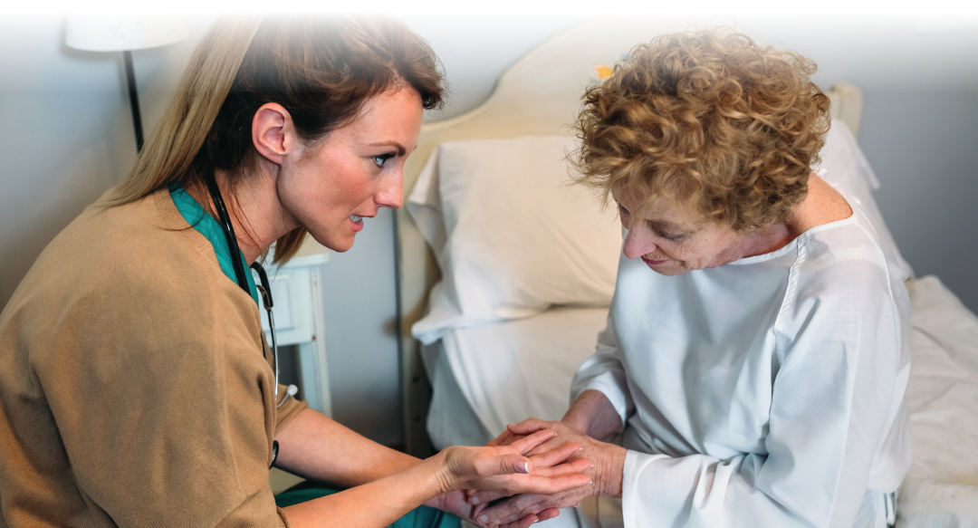 Female doctor giving encouragement to elderly patient by holding her hands